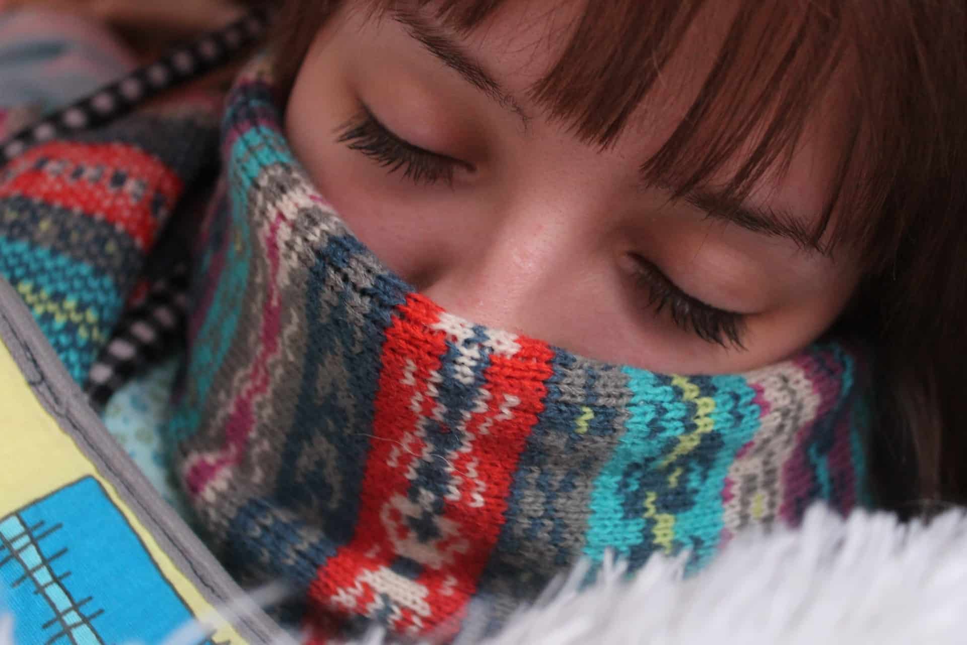 A woman wraps up with a scarf and blankets to avoid the cold