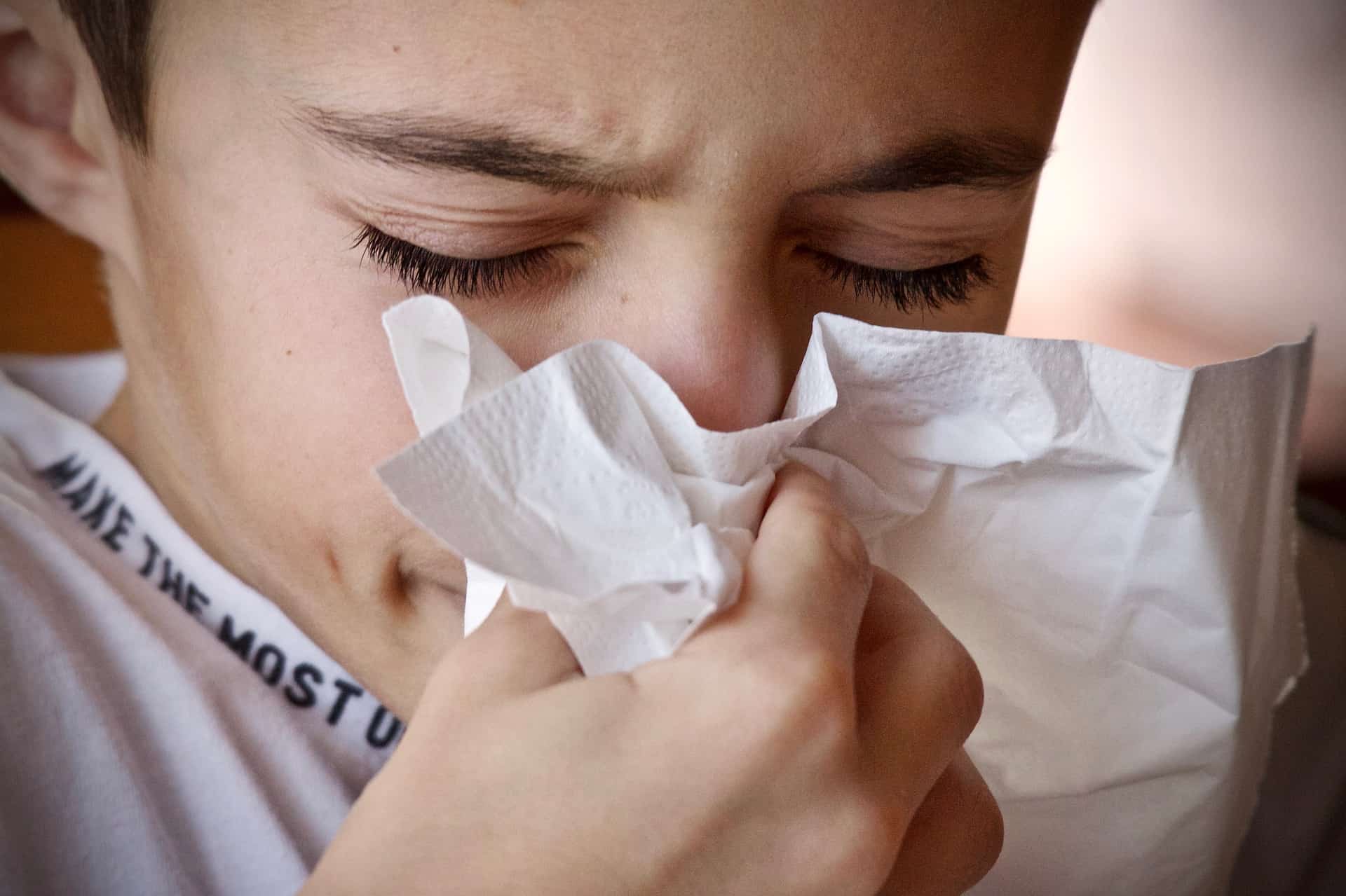 A young girl blows her nose because of allergies